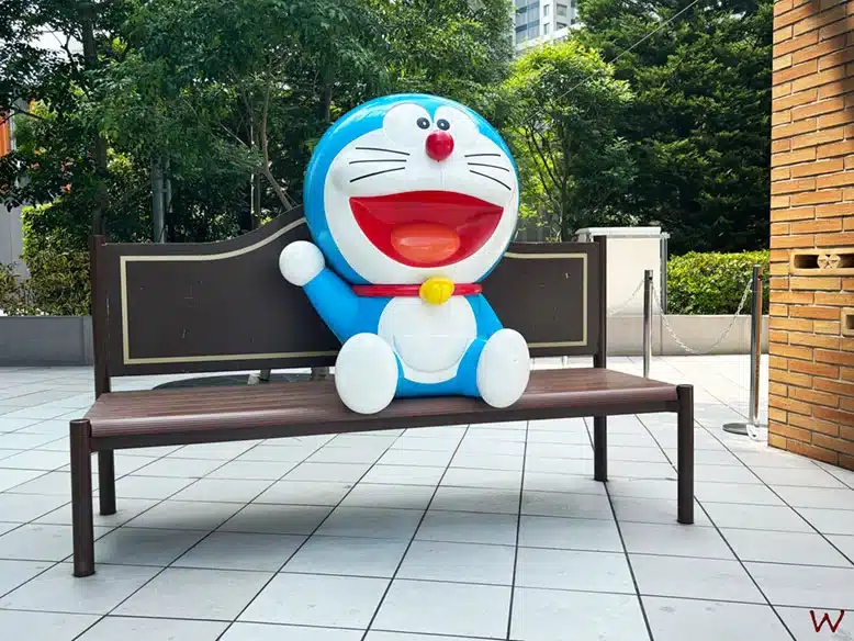 Doraemon sentado en un banco junto a la tienda de Doraemon en Tokio